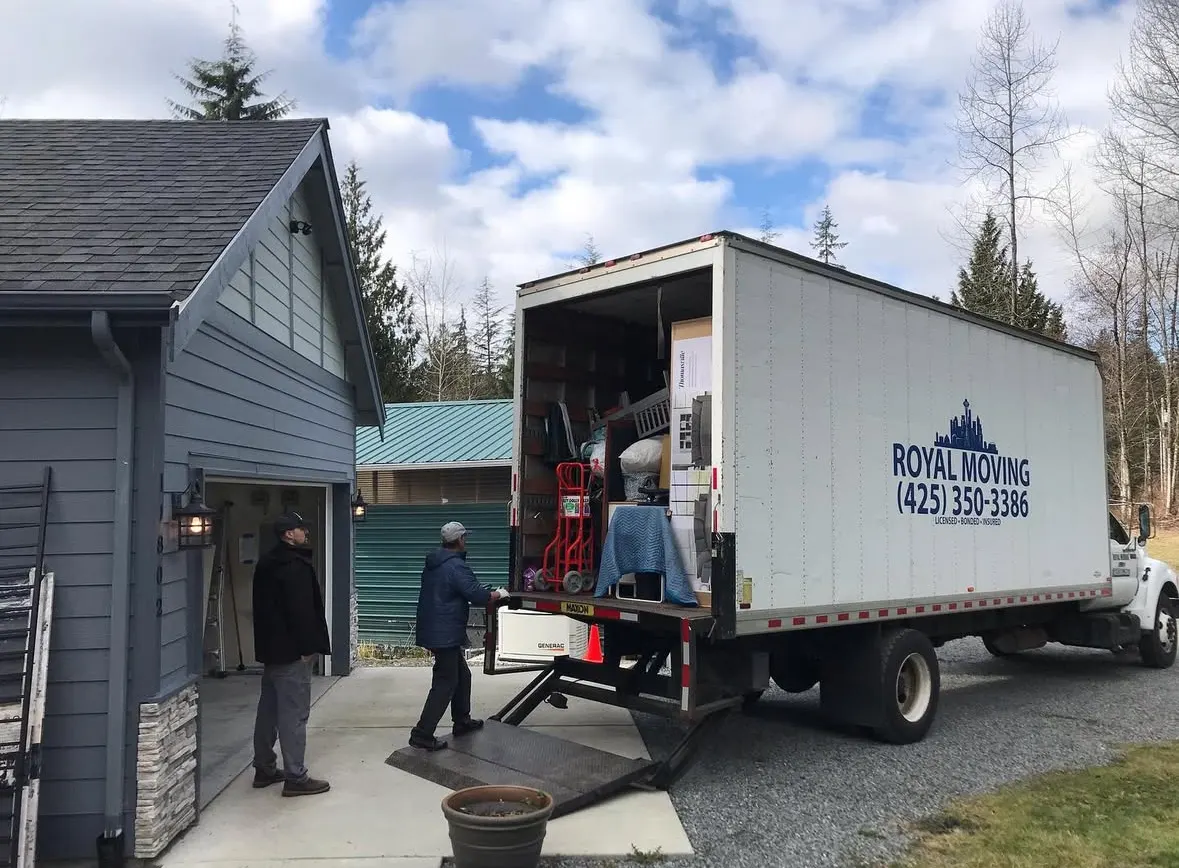Two movers carrying furniture up the ramp at a house