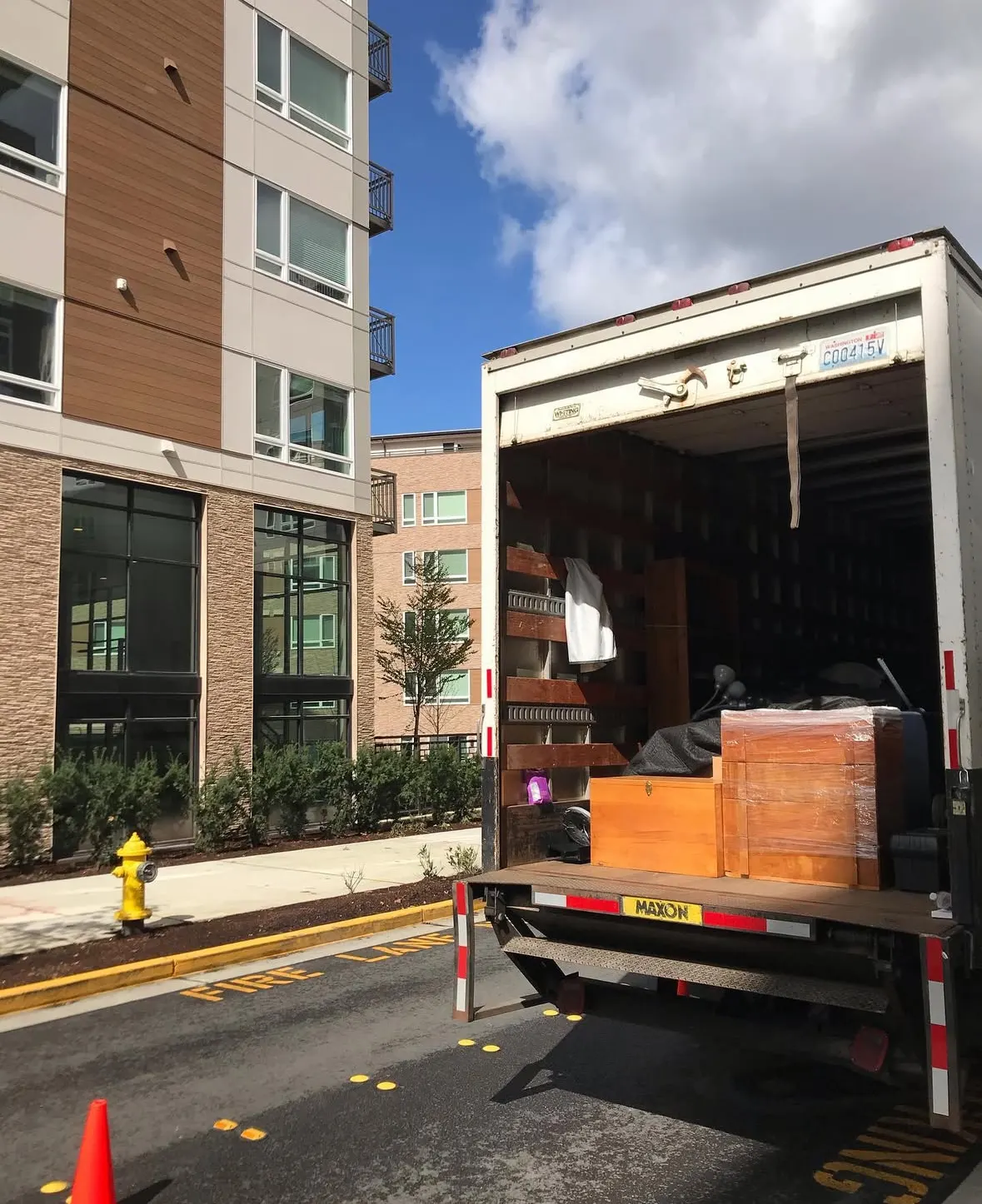 The truck at an apartment building with furniture on the liftgate
