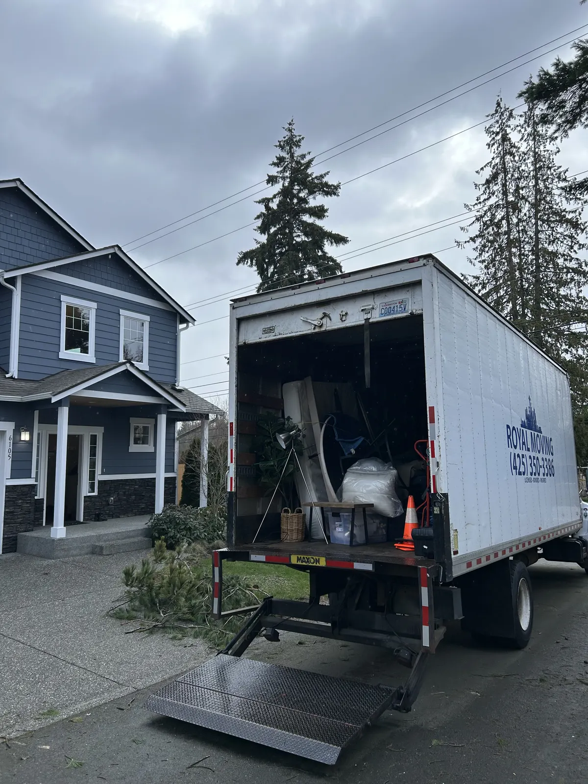 The truck backed up to a blue house with the liftgate down